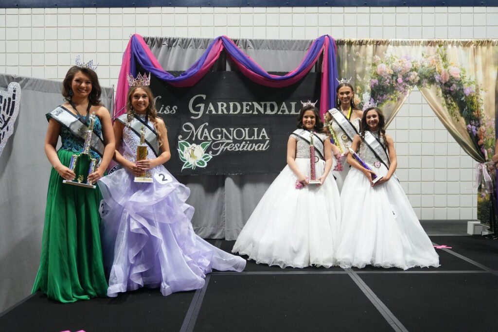 Girls of different ages in pageant dresses.

