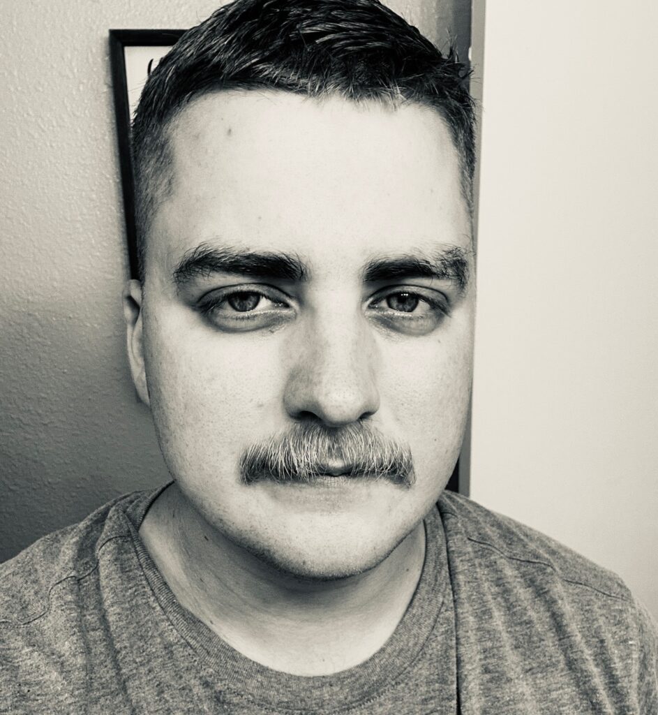 black and white image of man close up with mustache wearing a t shirt.